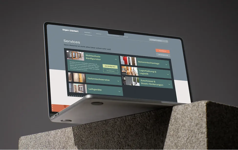 A laptop on a stone block displays the services page of the Etges & Dächert website.