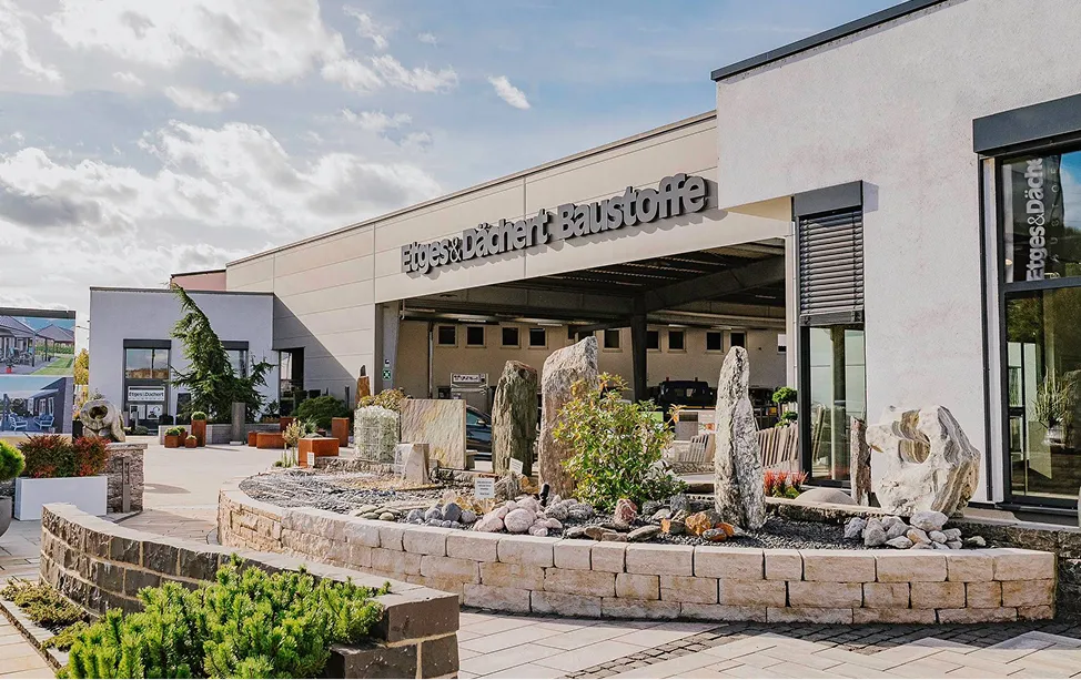 Exterior view of the Etges & Dächert Baustoffe premises with stone and plant displays.